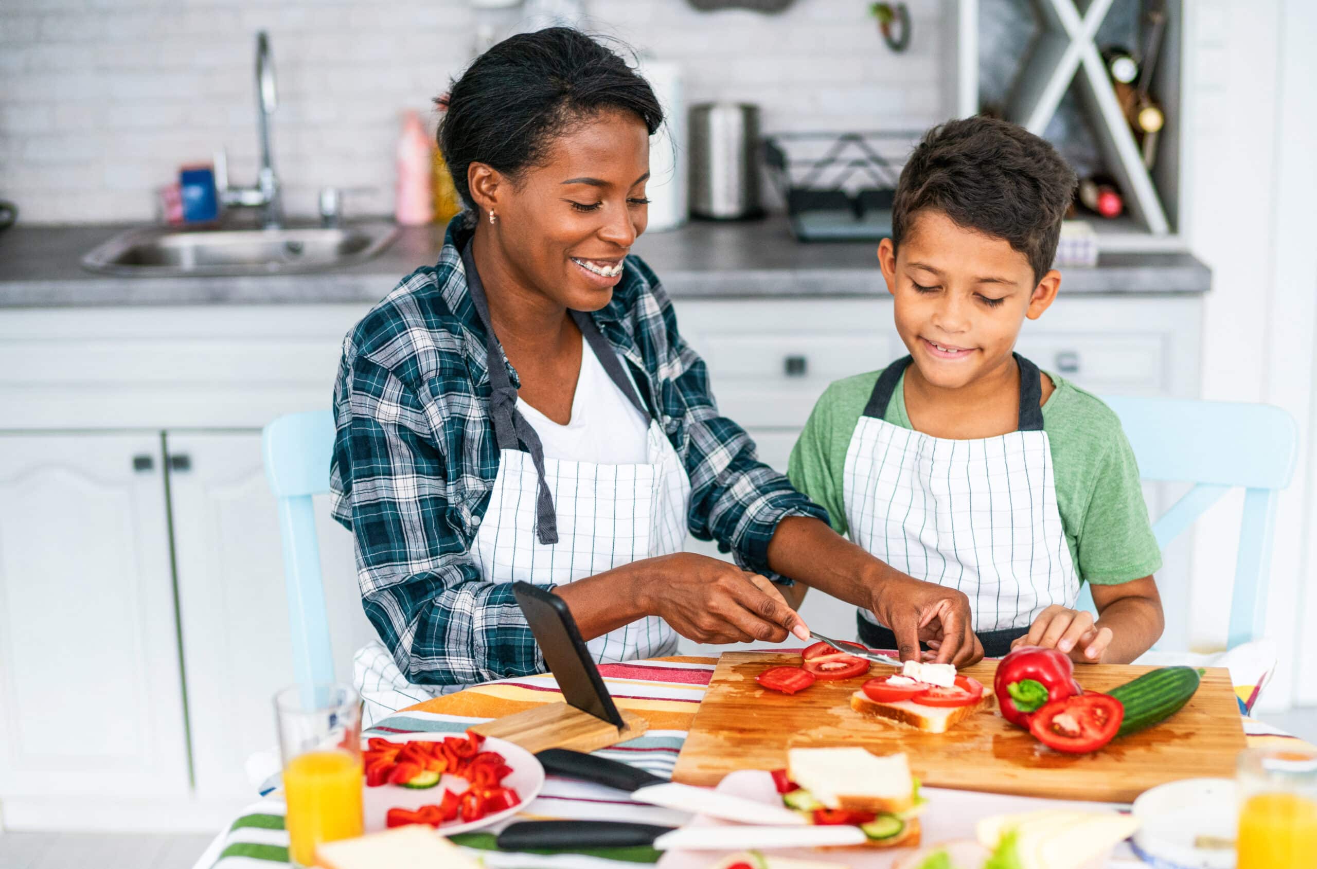 Young African-American Mother And Her Cute Son Preparing Healthy And Tasty Sandwiches Together In The Kitchen.