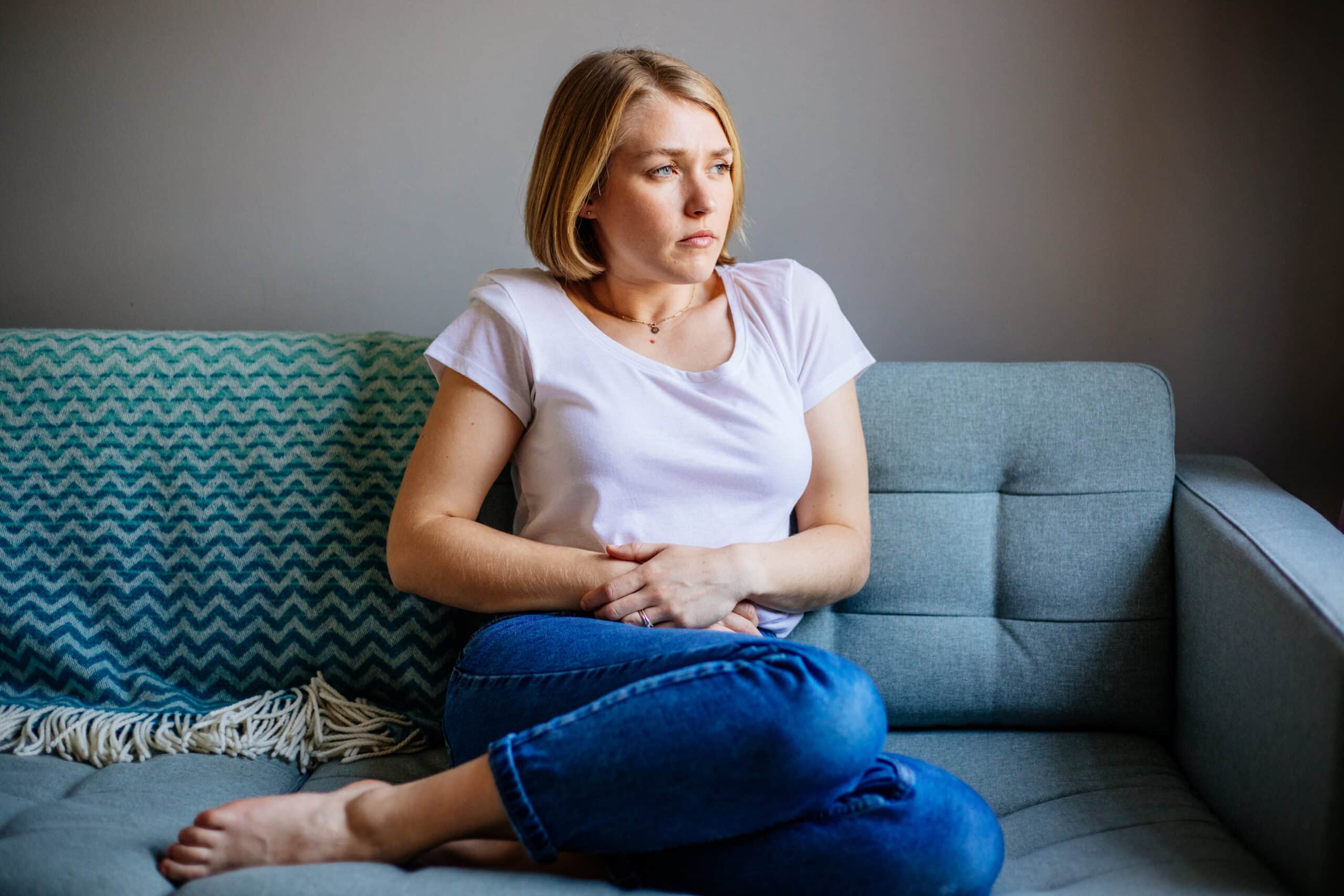 Woman Experiencing Stomach Pain While Lying On The Sofa At Home