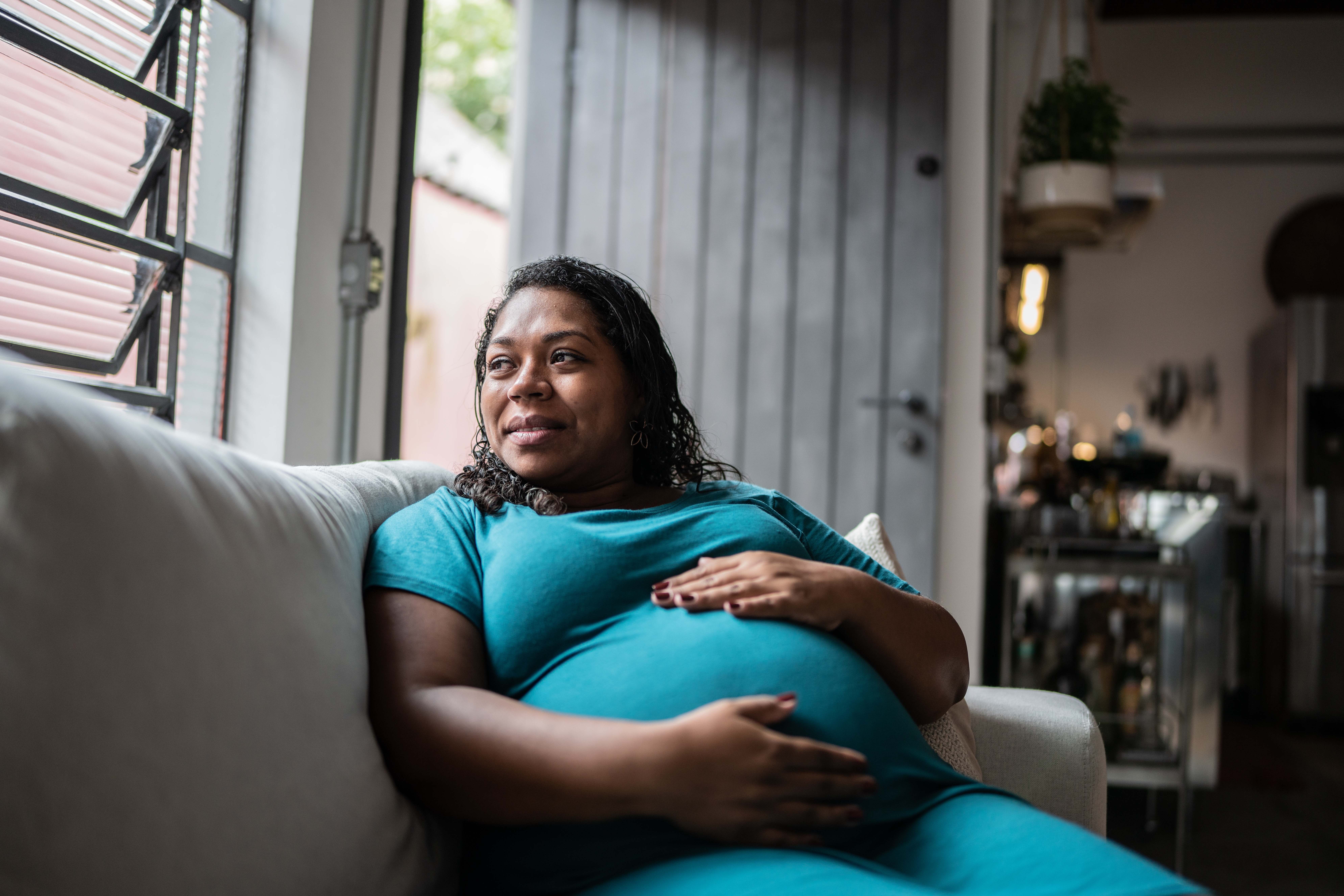 Pregnant Woman Touching Her Belly And Contemplating At Home