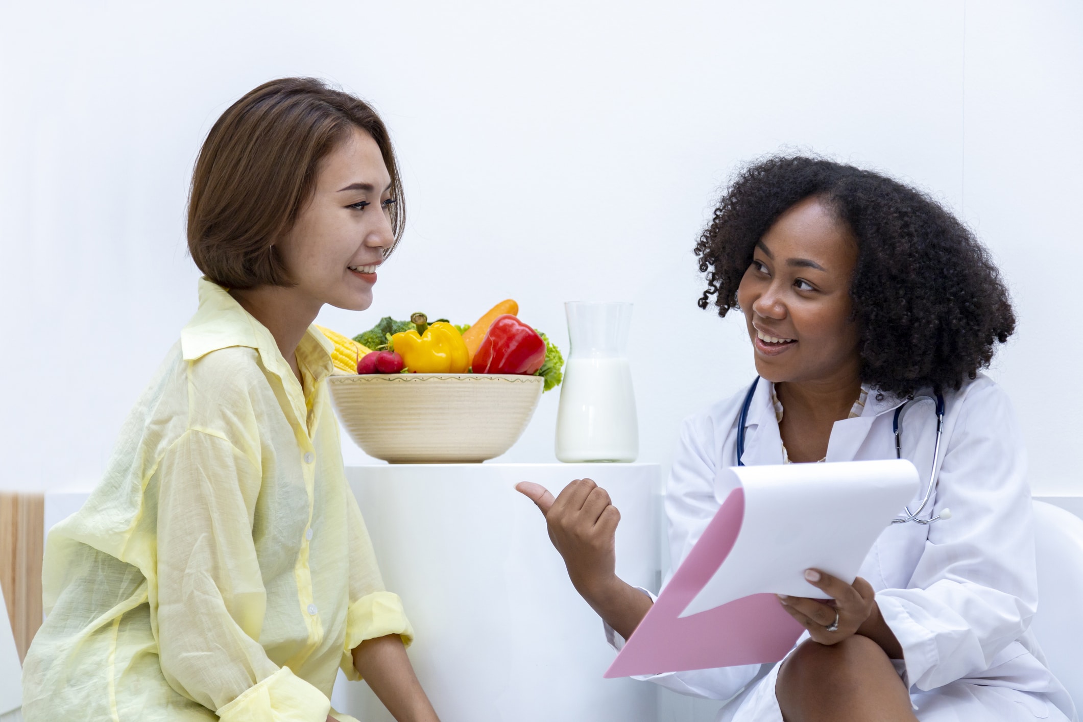 Nutrition Counseling 1 Dietitian Group African American Nutritionist With Bowl Of Variety Of Fruit And Vegetable Giving Advice To The Client For Healthy Diet And Vitamin Booster