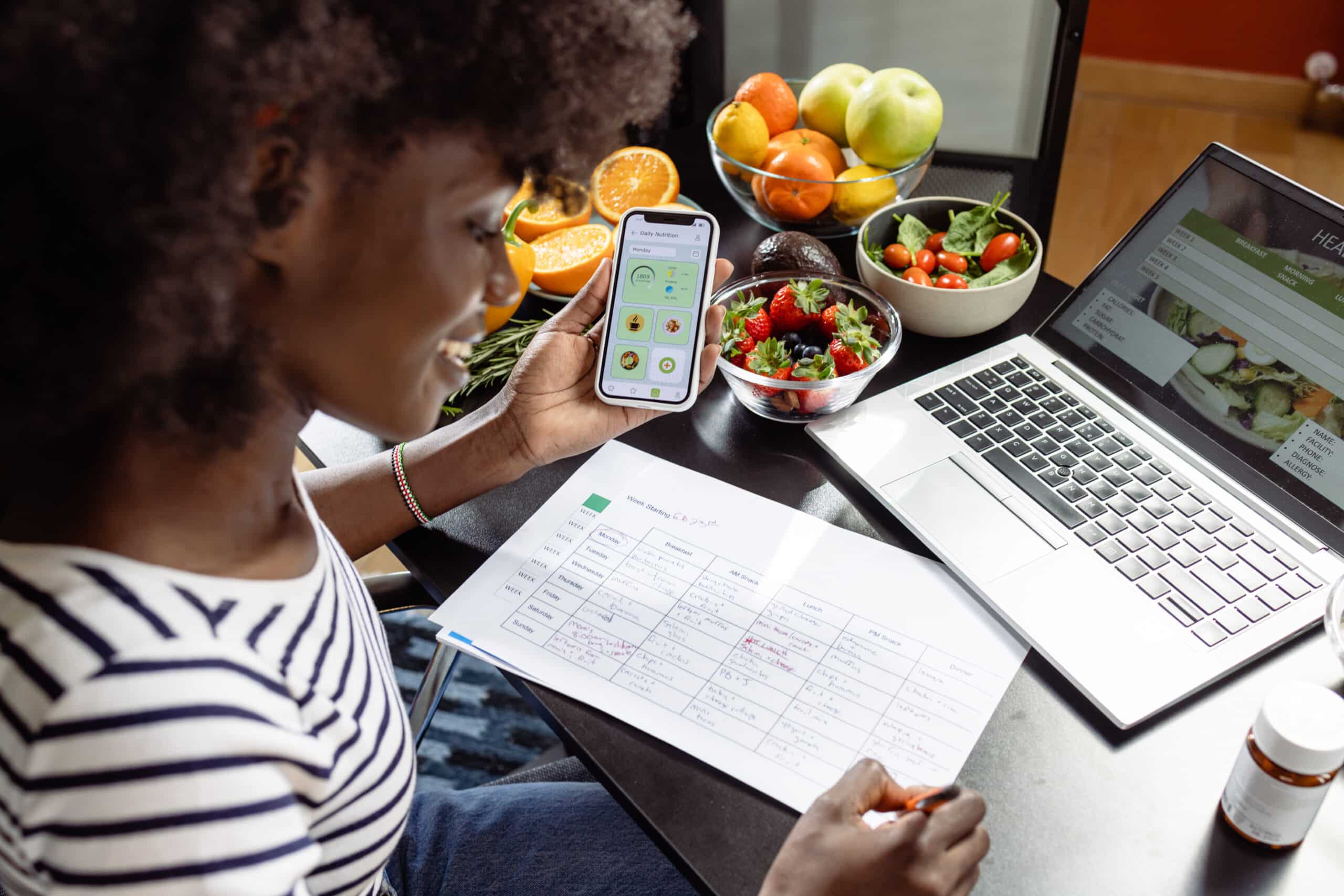 A Young African American Nutritionist Is Using A Diet Tracker Mobile App On Her Smart Phone To Create A Nutrition Plan For The Clients