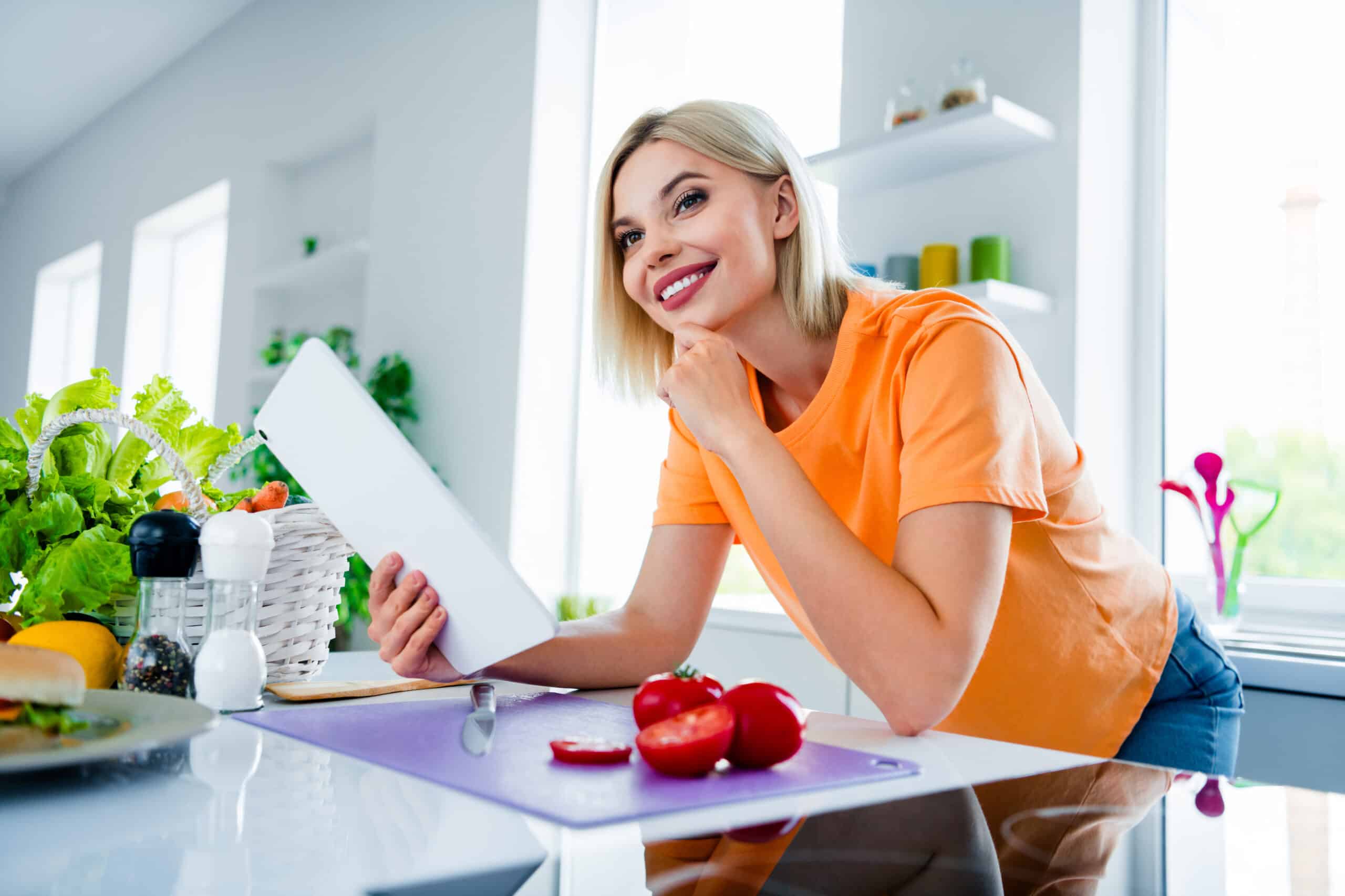 Photo Of Dreamy Housewife Lady Using Modern Technology Browsing Recipe For Perfect Dinner Husband In Kitchen.