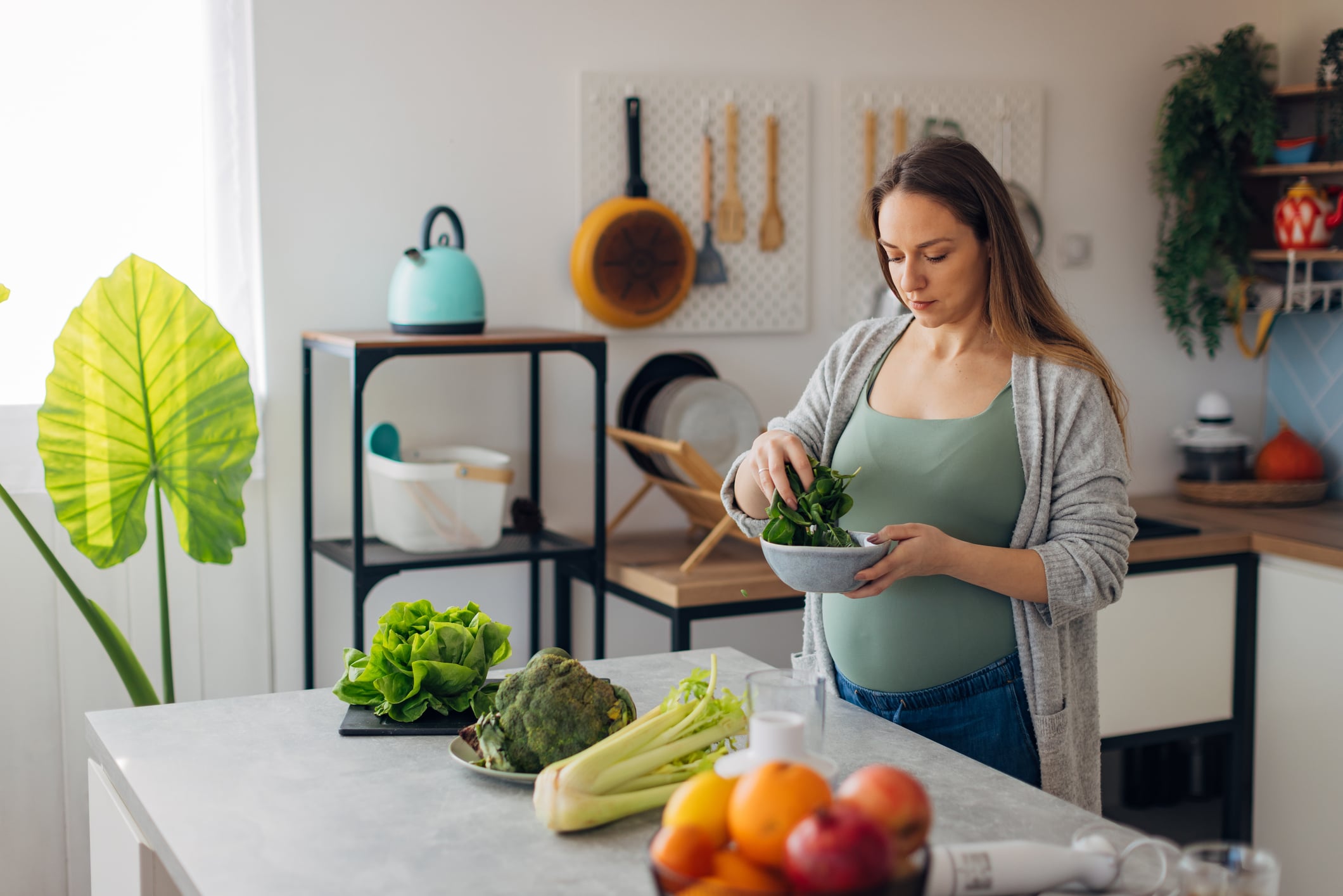 Pregnancy Diet 1 Dietitian Group A Pregnant Woman Is Preparing A Salad In The Kitchen From Green Vegetables. She Is Holding A Bowl In Her Hands And Mixing The Vegetables In It