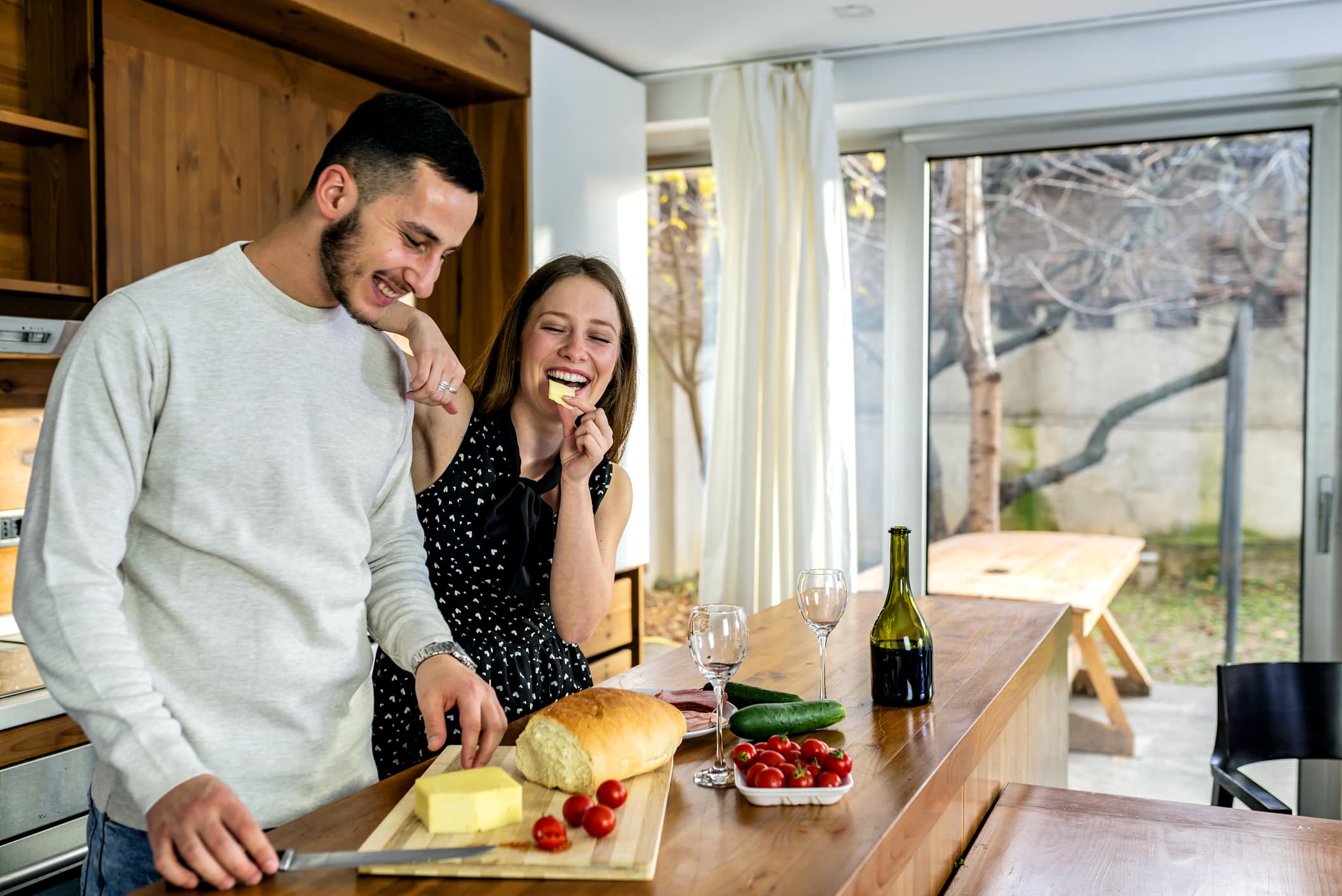 Attractive Young Couple Enjoying Anniversary With Delicious Appetizers And Bottle Of Wine