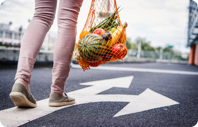 Person walks down a roadway with a red mesh bag full of foods from their dietitian approved meal plan