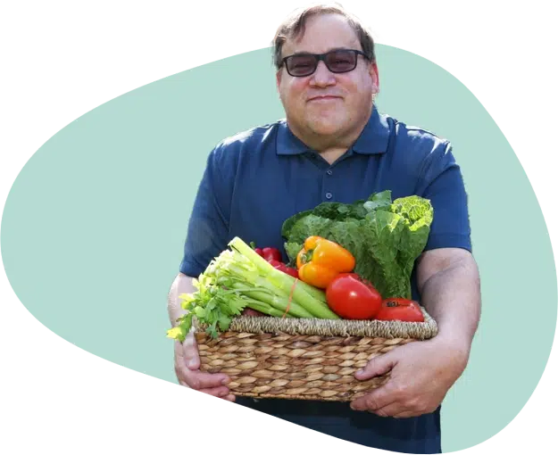 A man with autism holding a basket full of healthy veggies