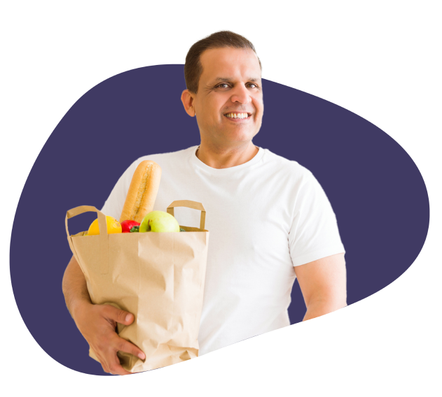 A man with a bag full of veggies and fruits
