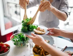 person putting salad on someone's plate