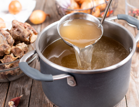 ladle stirring soup in a pot on the table