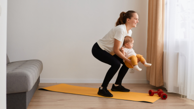 Lady in squat position while holding baby with both hands