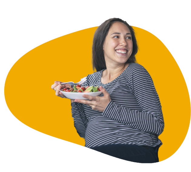 A smiling pregnant lady with a plate of fruit salad