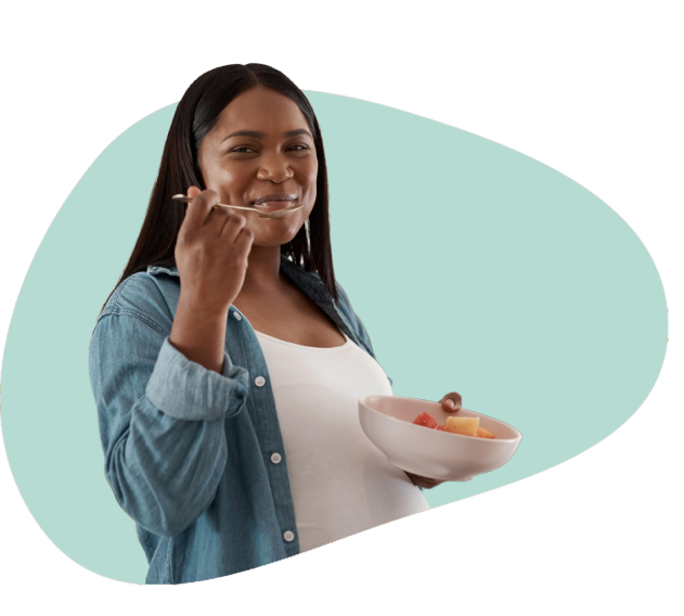 A lady eating from a bowl of fruits while smiling