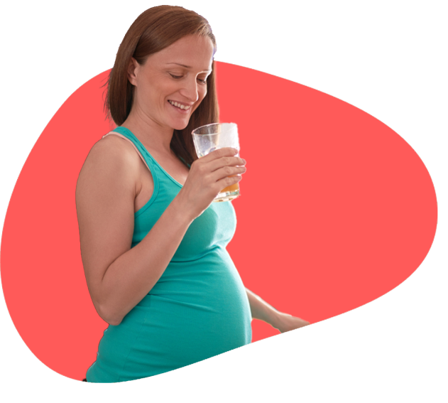 A pregnant lady holding a glass of juice she is holding