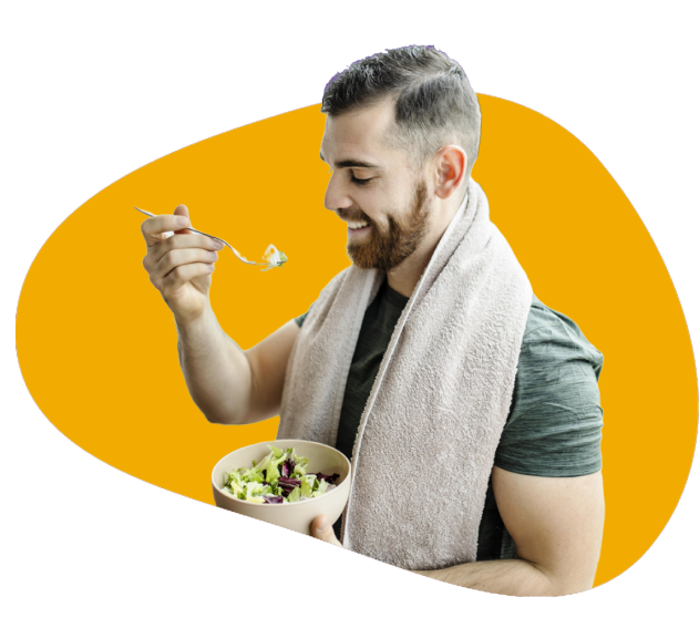 A muscular man with a towel around his neck eating from a vegetable salad bowl that he is holding