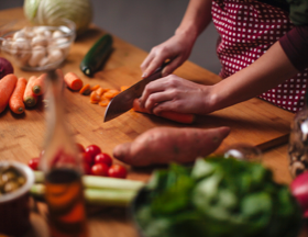 Someone cutting carrots on the table with other vegetables