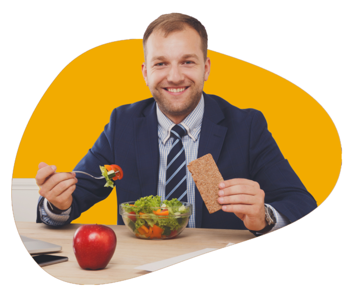 Persona smiles at the camera holding a cracker in one hand and a fork in the other as they eat their salad.