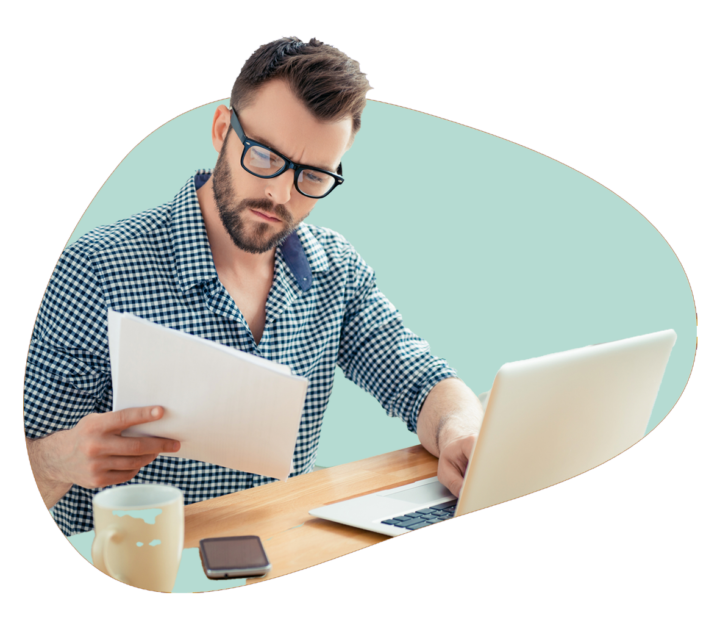 Person has one hand on their laptop keyboard and the other holding papers in the their hand.