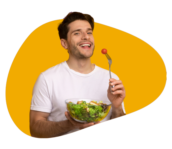 Holding a fork with a tomato in one hand and a bowl with chicken salad in the other, a person smiles at the camera.
