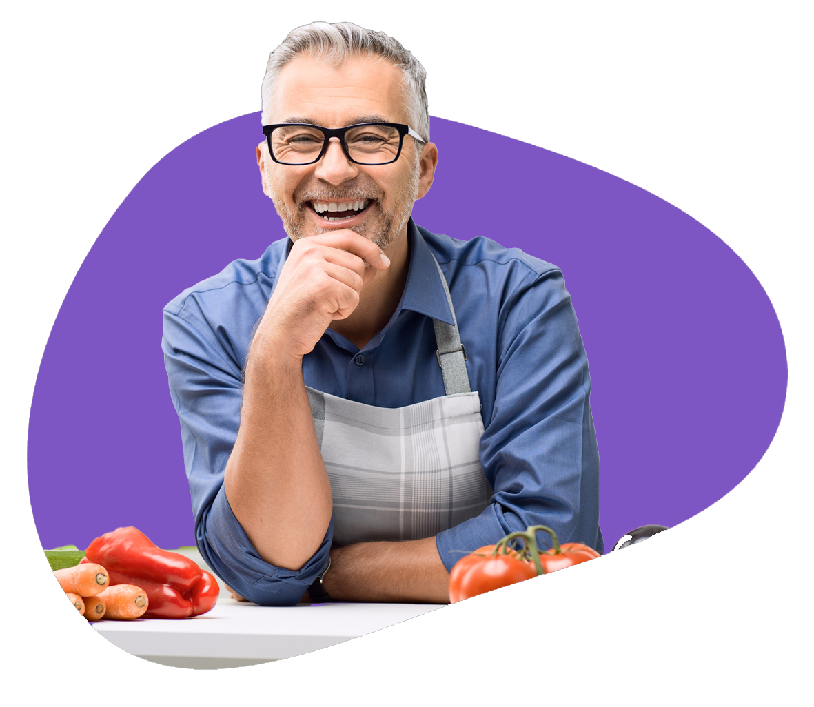 Person smiles at the camera, leaning against a countertop, with fresh vegetables in front of them.