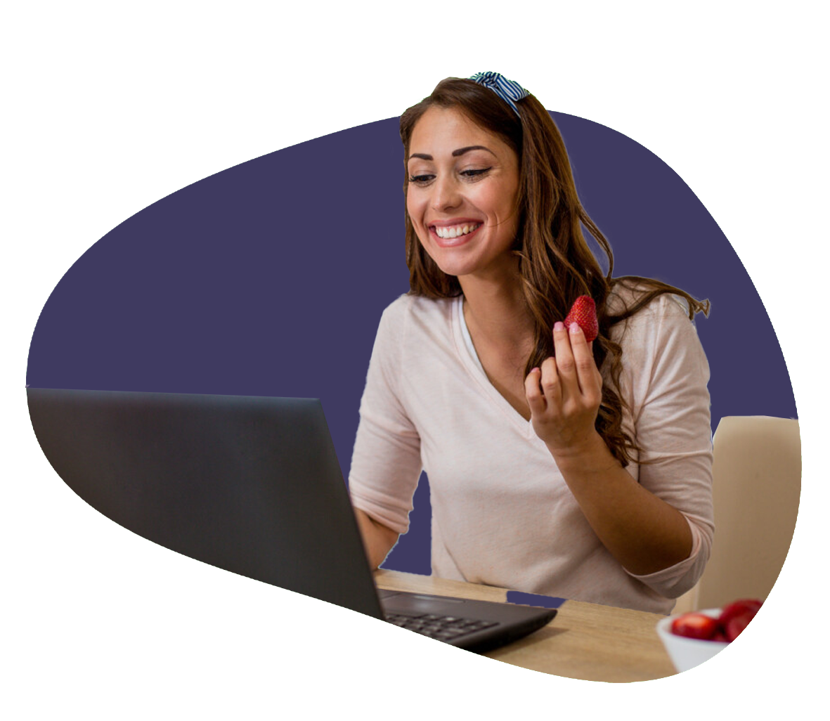 Dietitian smiles at their laptop as the hold a strawberry