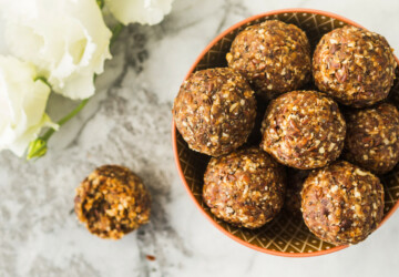 Energy protein balls with healthy ingredients on marble table. Home made with dates, peanut butter, flax and chia seeds, oats, almond and chocolate drops