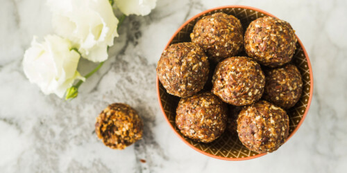 Energy protein balls with healthy ingredients on marble table. Home made with dates, peanut butter, flax and chia seeds, oats, almond and chocolate drops