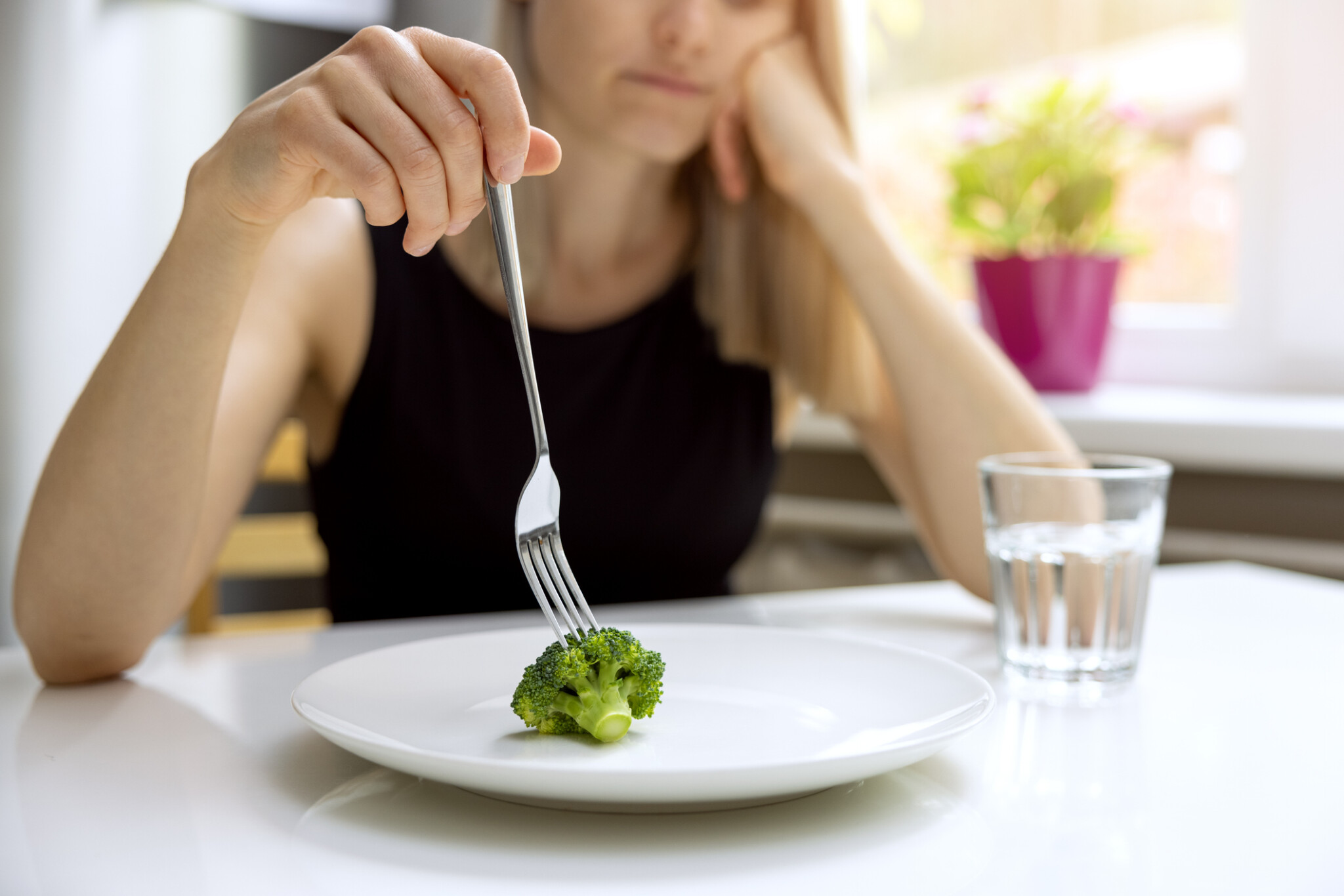 Unhappy woman looking at small broccoli portion on the plate