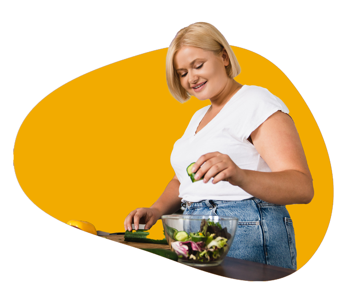 A person stands at their kitchen counter cutting cucumber and adds it to their salad.