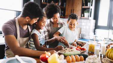 A family stands in the kitchen, preparing homemade food together.