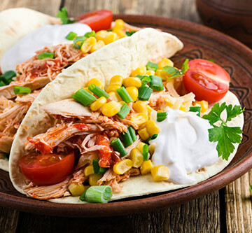 Homemade slow cooker chicken taco with corn served on rustic ceramic plate on wooden table, Mexican style