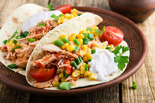 Homemade slow cooker chicken taco with corn served on rustic ceramic plate on wooden table, Mexican style