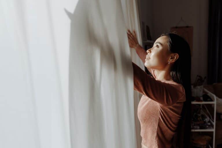 Woman Opening Curtains In Hopeful Morning Light, Representing Pcos Diet And Fertility Support