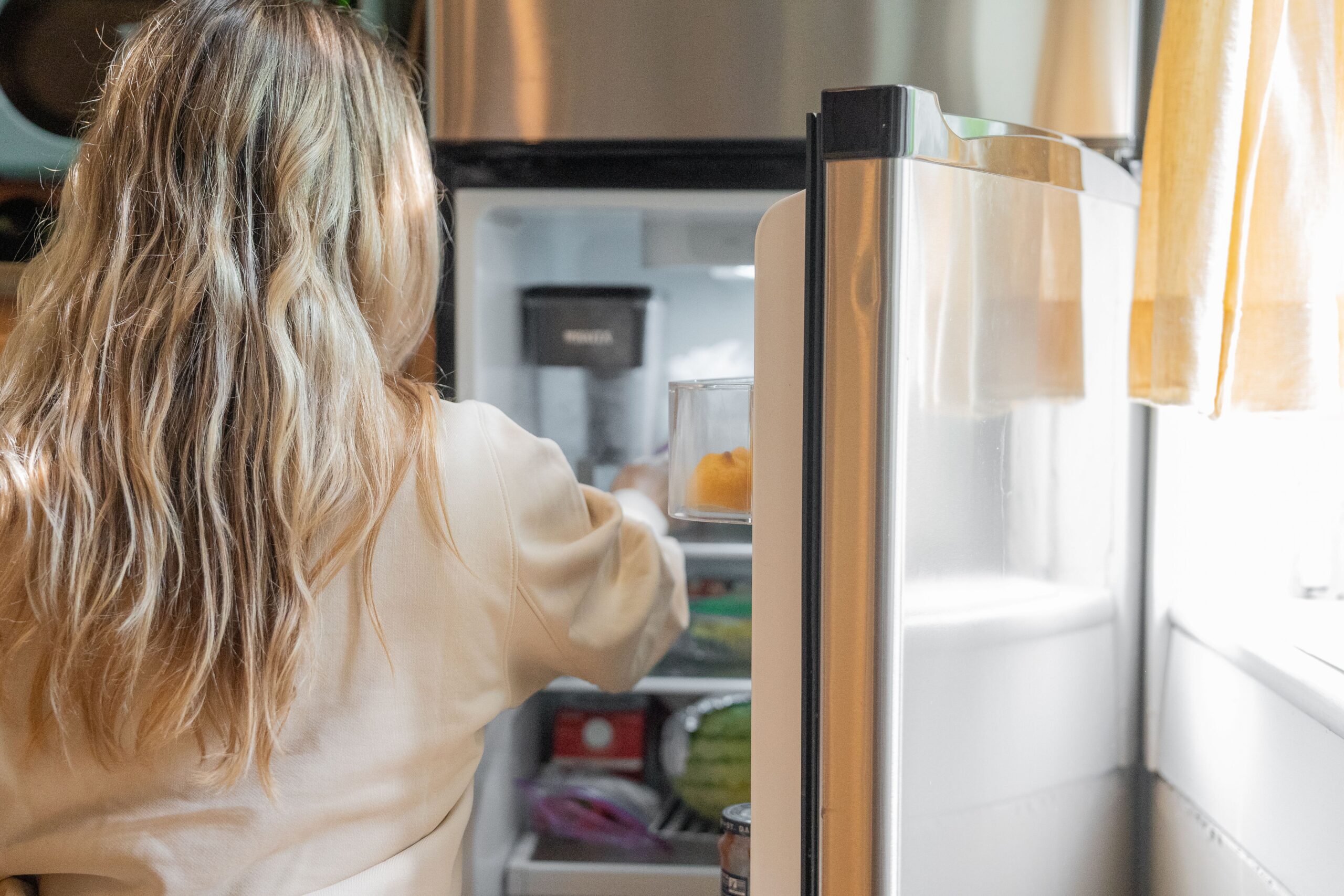 Woman Reaching Into Open Refrigerator